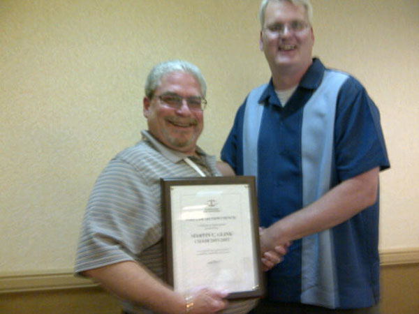 Chair Kevin Veugeler presenting last year's chair Marty Glink with a plaque of appreciation for his efforts