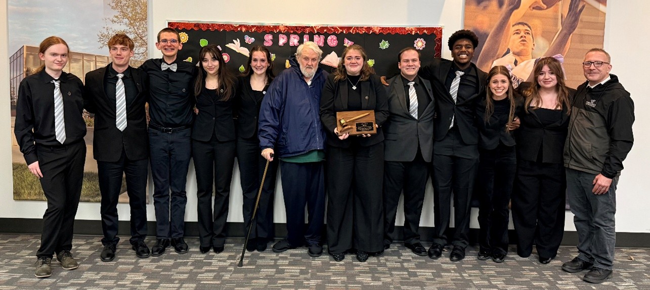 A photograph of the team from Normal West High School with their coach and award
