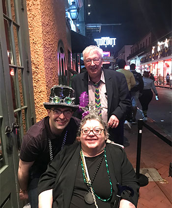 three people decked out in Marti Gras attire