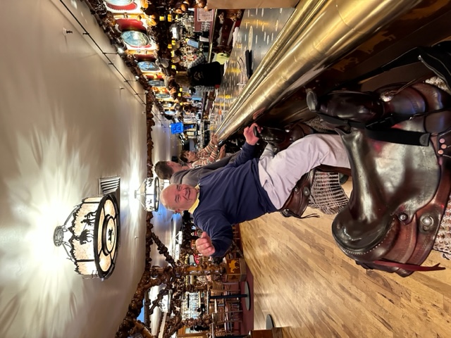 man sitting in a bar stool that has a saddle as a seat