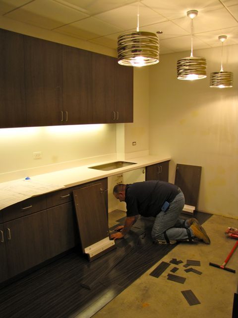 A construction worker installs flooring in the break rooom.