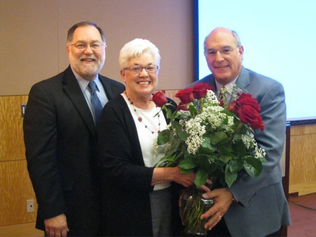  ISBA Executive Director Robert Craghead and President Mark Hassakis present roses to JoAnn Hibbs, Administrative Assistant to the Executive Director during the Board of Governors meeting in St. Louis. Hibbs is retiring from the Association in July after 34 years of service.