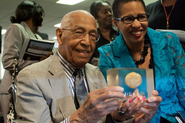 Judge Leighton and Judge Ann Claire Williams display a rock which is encased in plastic, dated March 17, 1936. That is when Judge Leighton, as a young man, found the rock amidst potatoes he was peeling at a restaurant job. He decided to keep the rock, and it has accompanied him throughout his life journey.