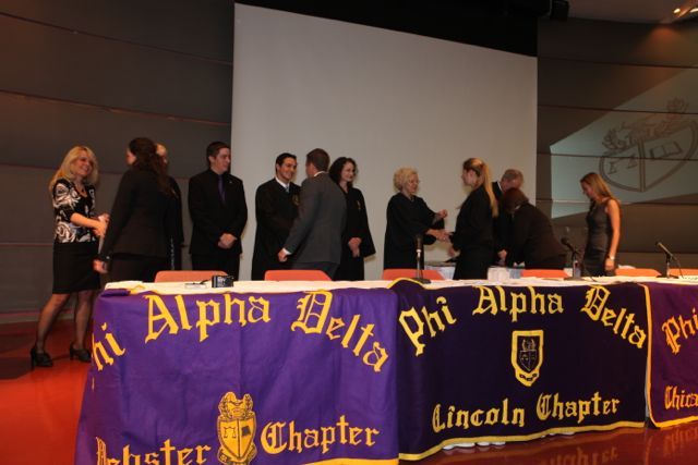 Phi Alpha Delta leaders congratulate each of the new members.