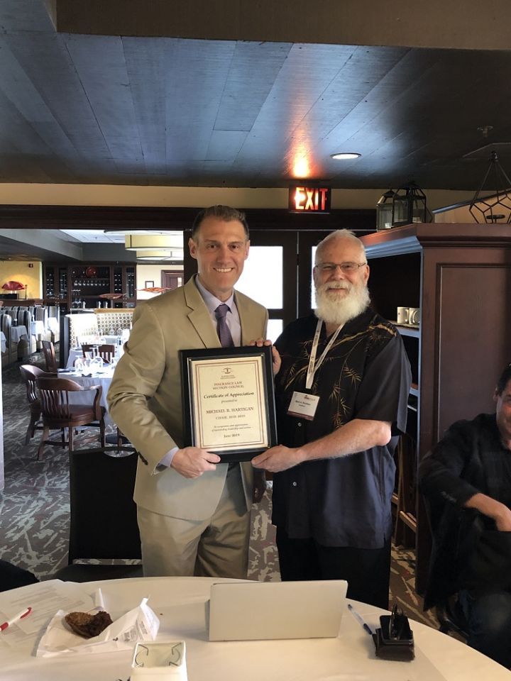 The Insurance Law Section Council's chair Mark Rouleau presents a plaque to ex-officio Michael Hartigan.