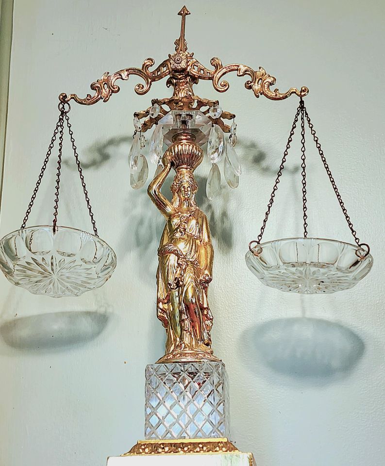 Michelle Rozovics: "After my Law School graduation, my mother and aunts went to the car and brought in a very heavy package, with many tiny tissue-paper-wrapped mini packages. They couldn’t stop laughing as I began unwrapping each gift. Tiny crystal teardrops on wires. OK, I like jewelry. Candy dishes? Then, the beautiful, golden, 2-foot-tall monstrosity. Her. They bought her at a second-hand thrift store and thought I would hate her. They thought she made a great joke gift. Nope. I love every gaudy, glorious inch of her. I have displayed her proudly in every office for 29 years. My Scales of Justice."