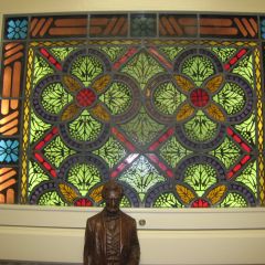 A statue of Abraham Lincoln stands in front of a stained glass window.