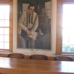 Jury table in Lincoln Courtroom with painting of Lincoln showing Farmers Almanac to jury in background.