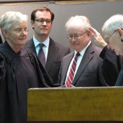 Mary Jane Theis (left) is sworn-in by retiring Chief Justice Thomas Fitzgerald as her son and husband look on.
