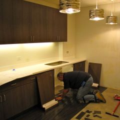 A construction worker installs flooring in the break rooom.