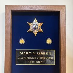 Martin Green: "The shadow box contains my badge from the Illinois Office of the Attorney General where I served as Executive Assistant Attorney General for Attorneys General Jim Ryan and Lisa Madigan. Underneath the badge are staff pins for Ryan and Madigan that include the scales of justice. Upon leaving the AOG for the private sector, I purchased the assigned numbered badge as a memento of my service. I am honored to have it hanging in my office as a reminder of the leadership and service of two exceptional Attorneys General who served our state in an exemplary manner."